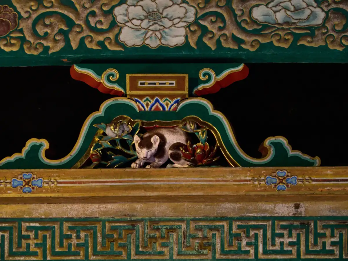 The carved Sleeping Cat (Nemuri-neko) above a doorway in the East Corridor of Toshogu, among painted peonies